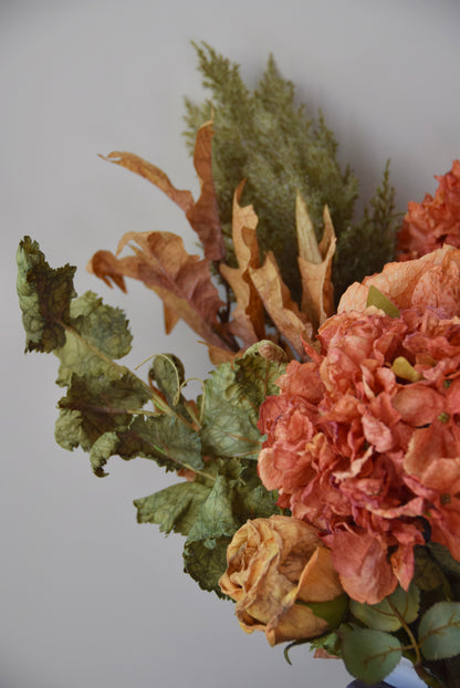 Bouquet of dried flowers with green and orange tones on a plain background