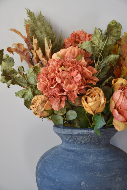 Decorative floral arrangement in a grey vase against a plain background