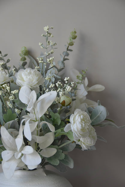 Artificial white flowers in a vase against a plain background