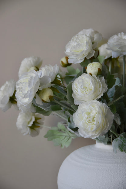 White flowers in a white vase against a plain background