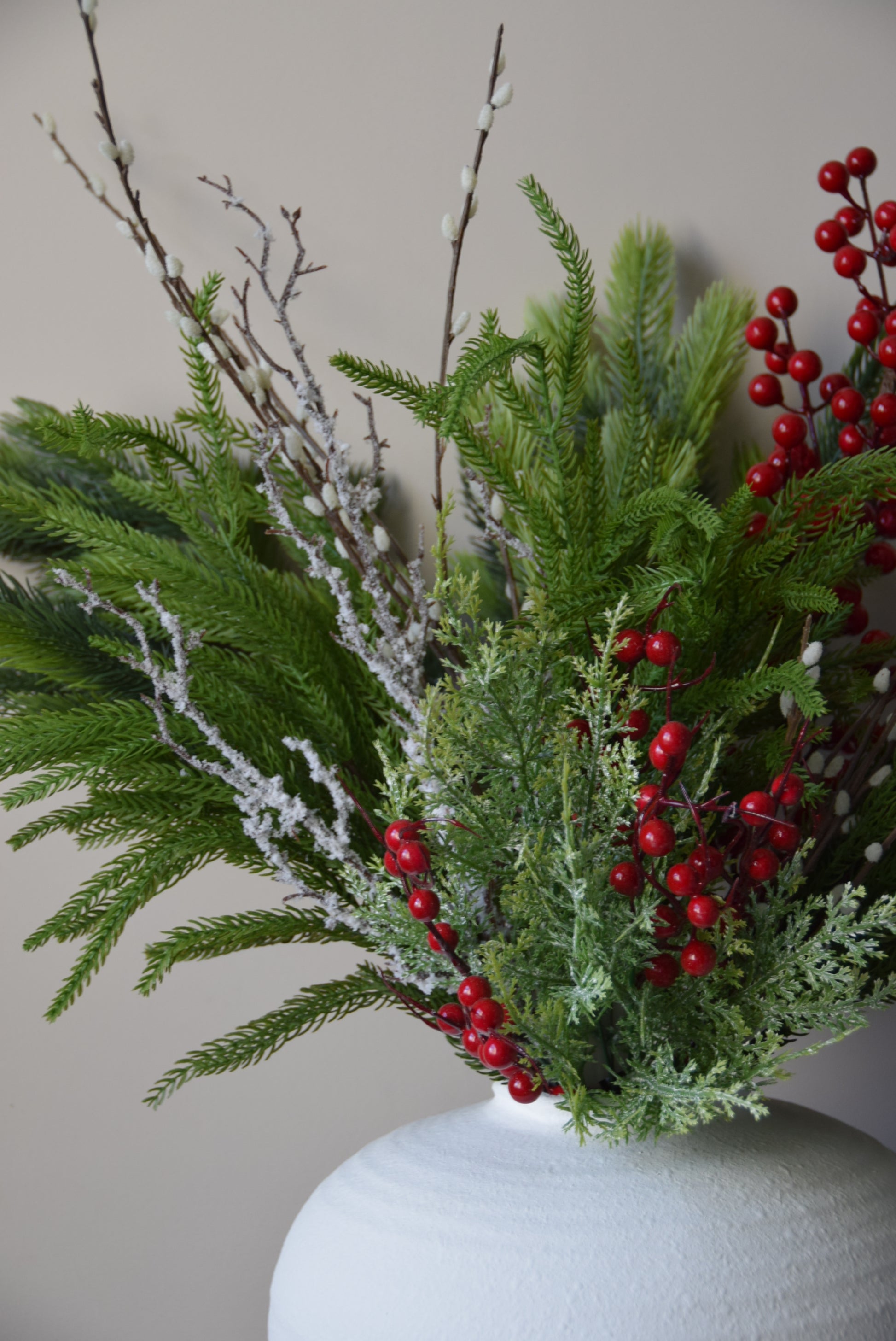 Decorative arrangement of greenery with red berries on a neutral background