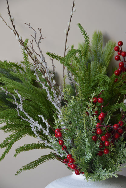 Decorative wreath with greenery and red berries on a plain background