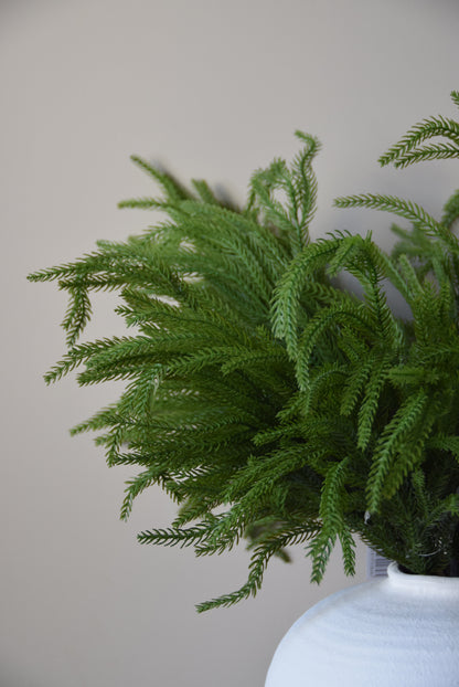 Green artificial winter foliage on a light grey surface