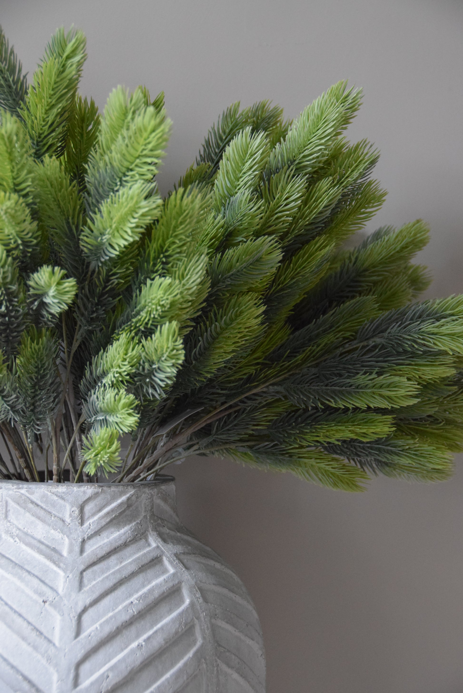 Close-up of a green artificial spruce branch against a neutral background
