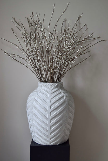 White textured vase with decorative branches on a plain background