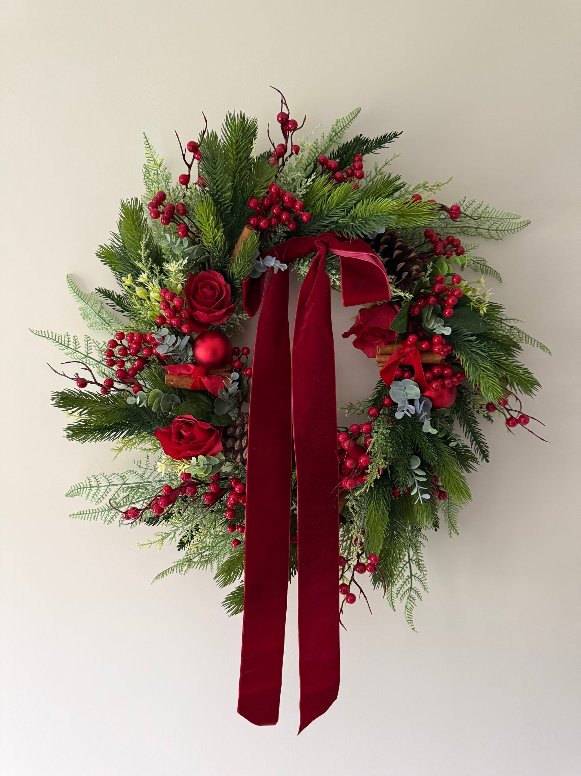 Christmas wreath with red ribbons and decorations on a plain background