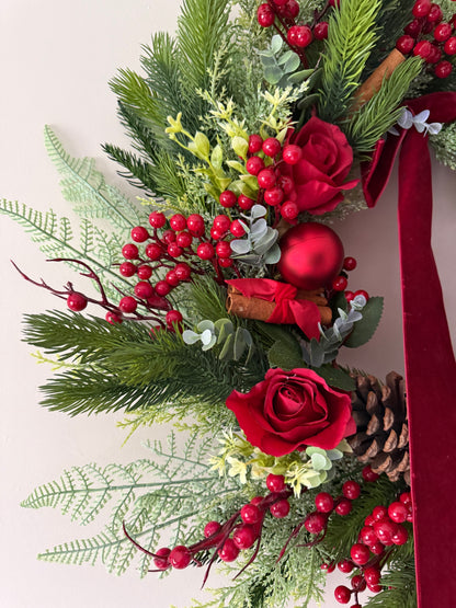 Decorative Christmas garland with red roses, berries, and greenery on a white background