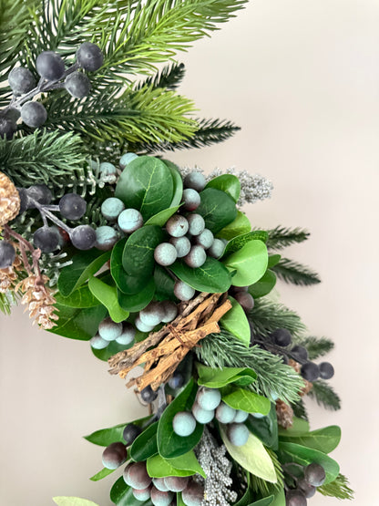 Decorative wreath with greenery and berries on a light background
