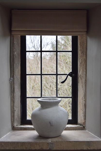White stone vase placed on a stone windowsill. Displayed in a country style house for home decor.