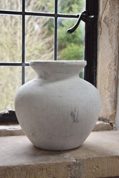 White stone vase placed on a stone windowsill. Displayed in a country style house for home decor.