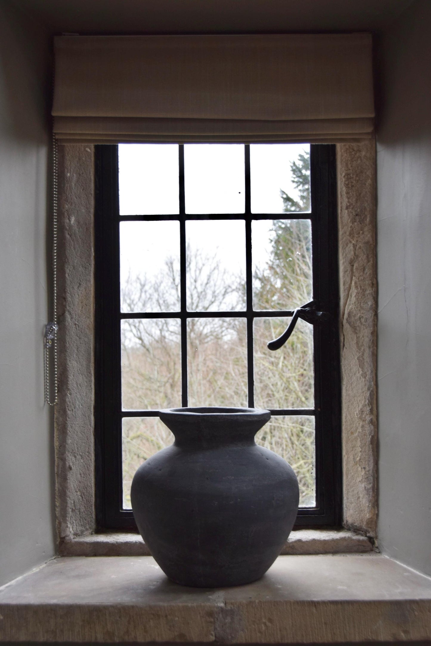 Grey stone vase placed on a stone windowsill in a country style house for home decor
