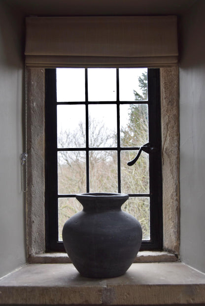 Grey stone vase placed on a stone windowsill in a country style house for home decor