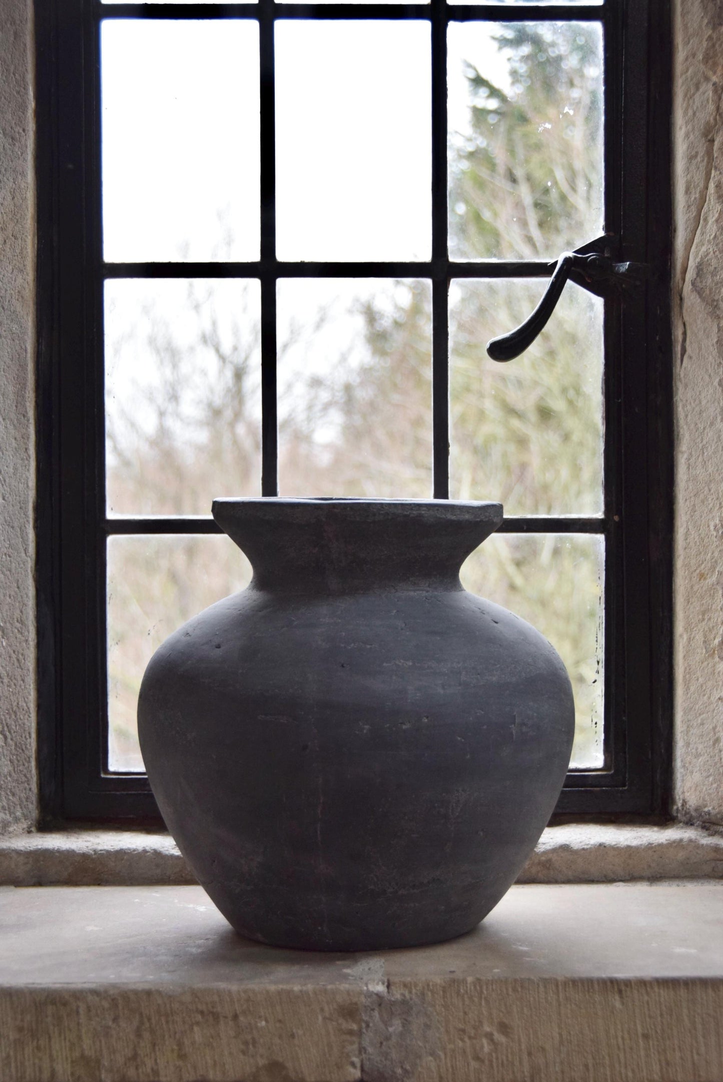 Grey stone vase placed on a stone windowsill in a country style house for home decor