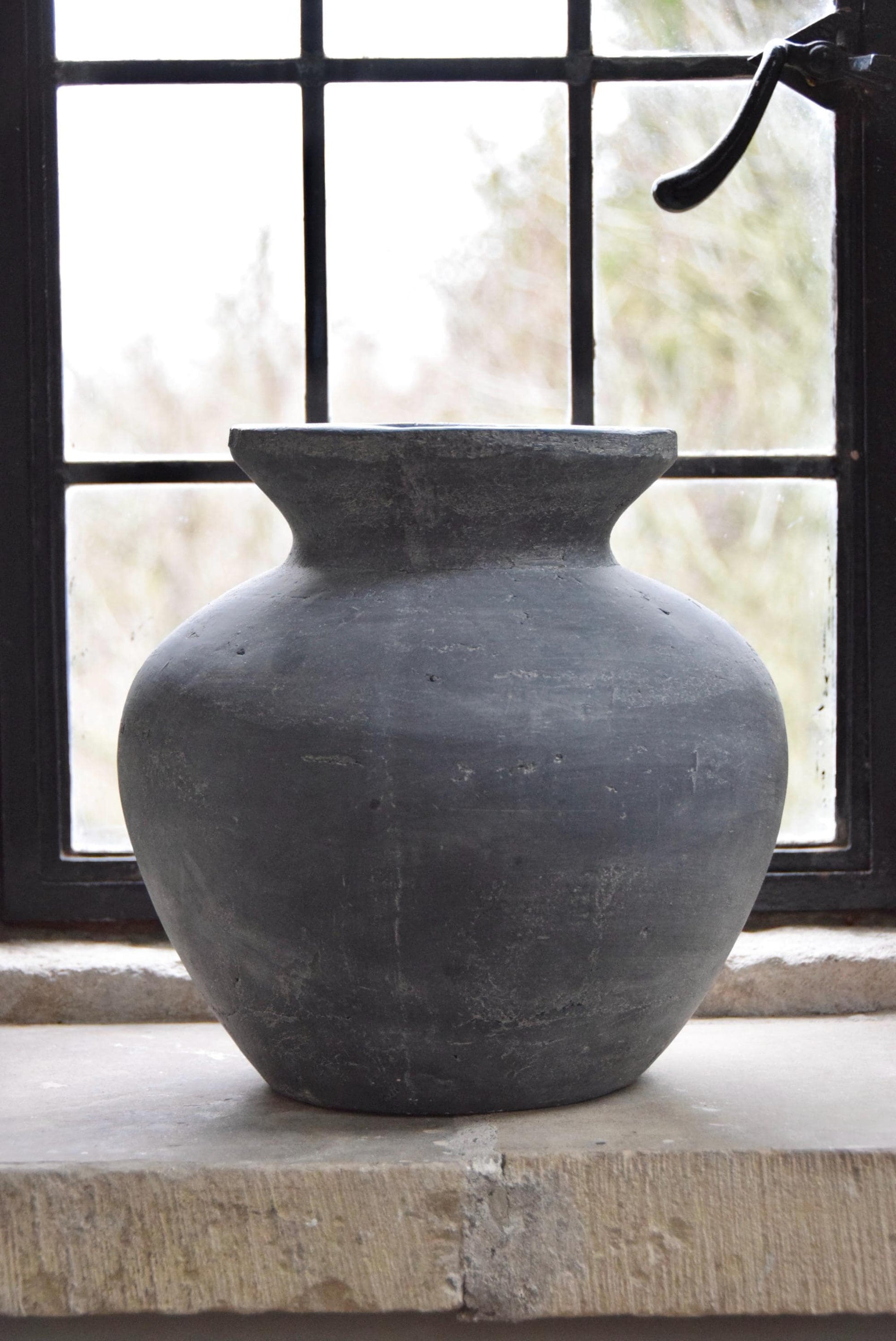 Grey stone vase placed on a stone windowsill in a country style house for home decor