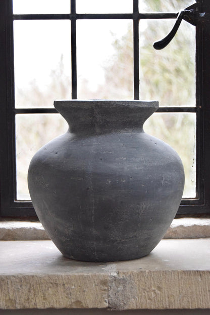 Grey stone vase placed on a stone windowsill in a country style house for home decor