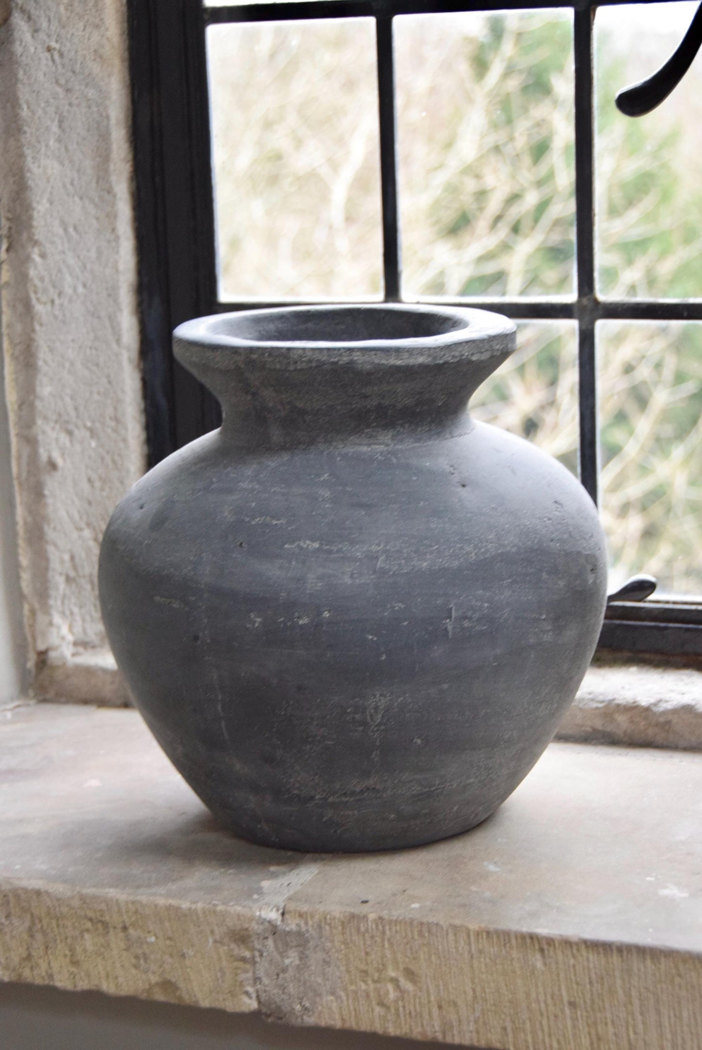 Grey stone vase placed on a stone windowsill in a country style house for home decor