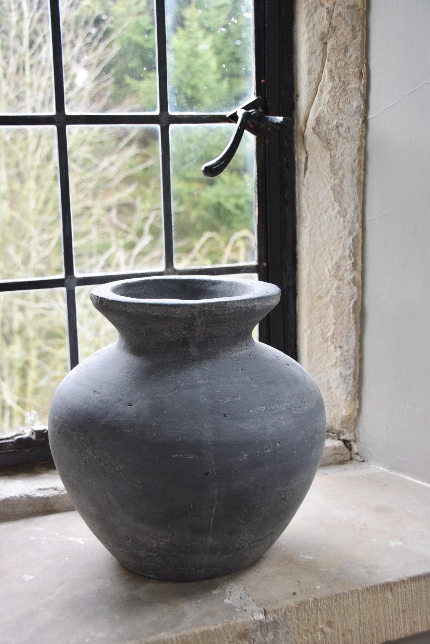 Grey stone vase placed on a stone windowsill in a country style house for home decor