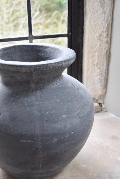 Grey stone vase placed on a stone windowsill in a country style house for home decor