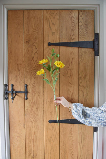 Yellow sunflower spray displayed against a country style wooden door.