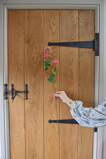 Pink pom pom spray displayed against a country style wooden door.