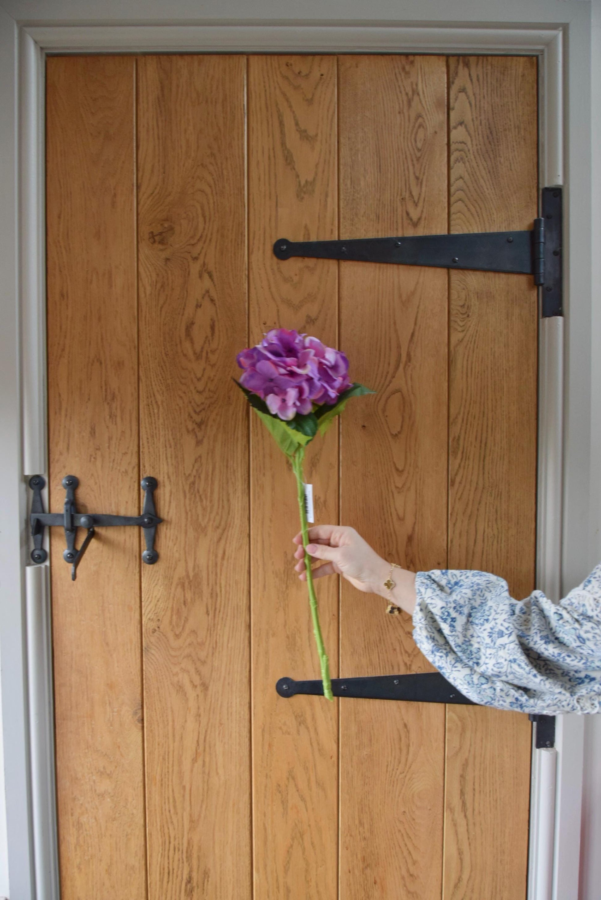 Purple hydrangea stem displayed in front of a rustic country style barn door