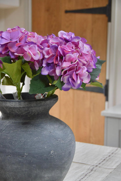 Grey vase placed on a kitchen counter top with purple hydrangeas arranged for home decor