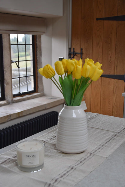 Yellow tulips set in a cream vase on a kitchen counter top in a country style kitchen for home decor