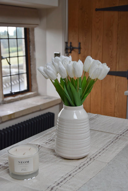 White tulips set in a cream vase on a kitchen counter top in a country style kitchen for home decor