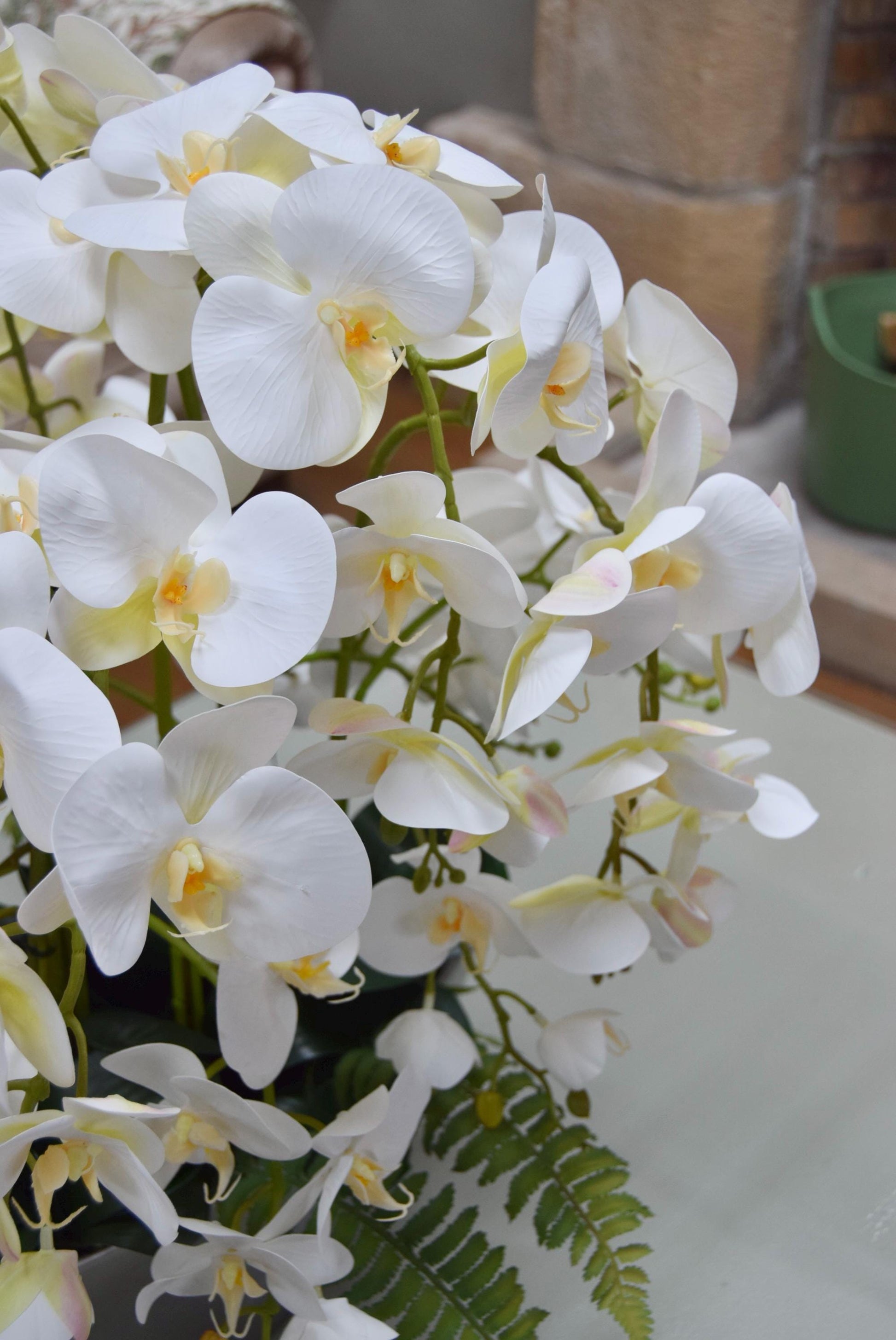 Silver ark bowl placed on a coffee table with an arrangement of white orchids. Arranged in a country style living room for home decor.