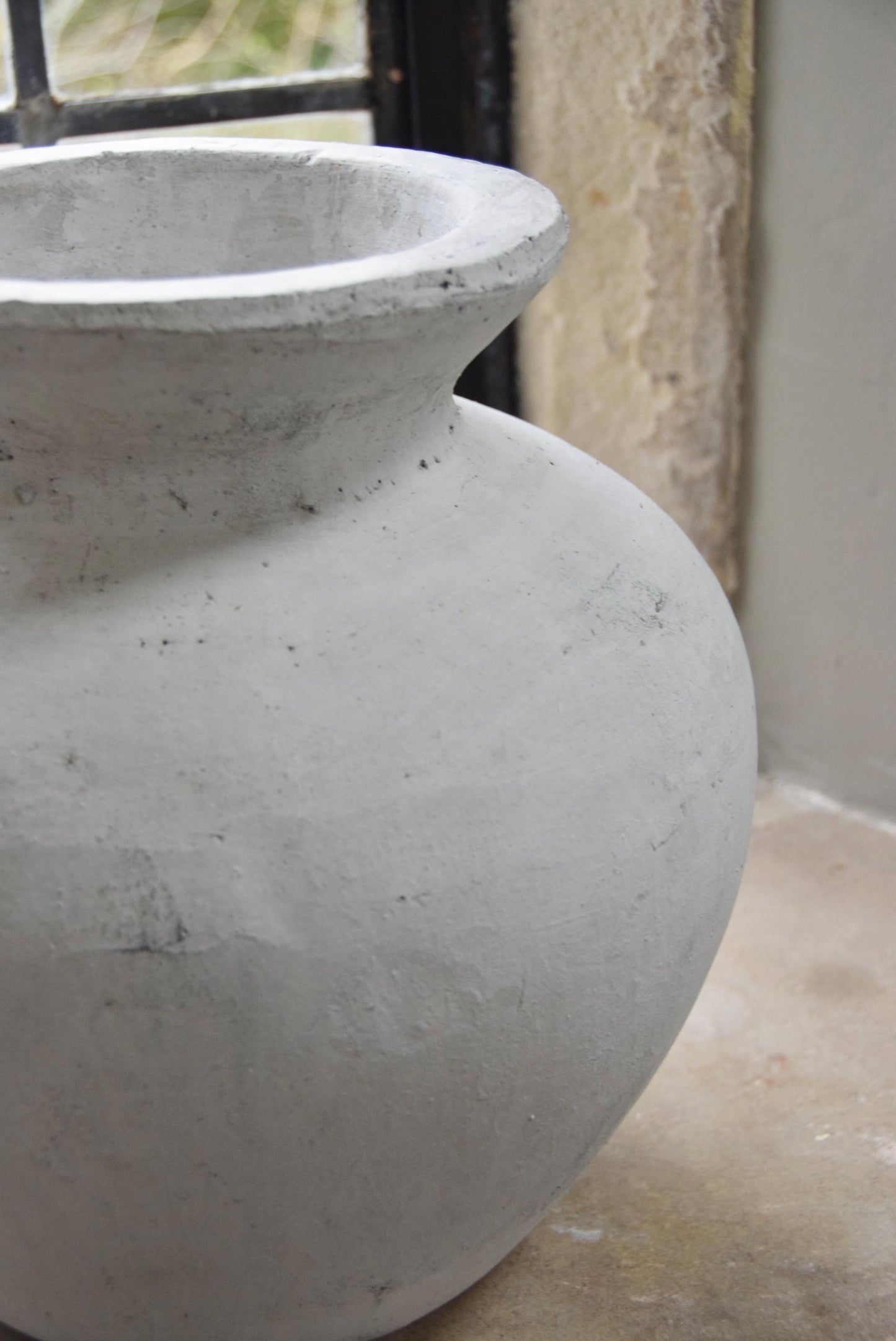 White stone vase placed on a stone windowsill. Displayed in a country style house for home decor.