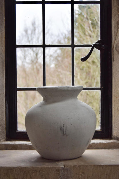 White stone vase placed on a stone windowsill. Displayed in a country style house for home decor.