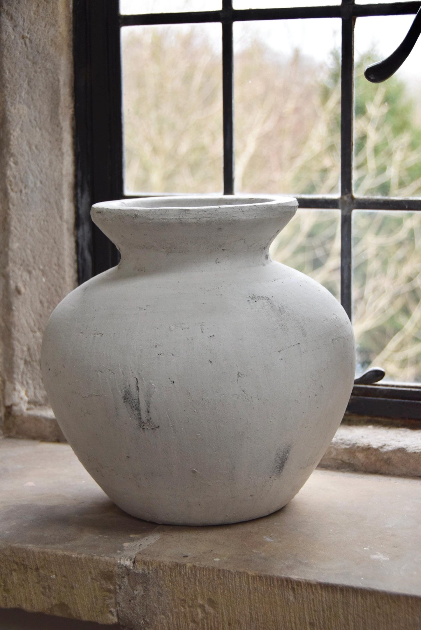 White stone vase placed on a stone windowsill. Displayed in a country style house for home decor.