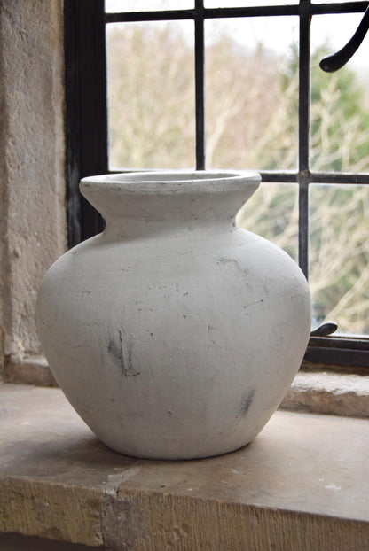 White stone vase placed on a stone windowsill. Displayed in a country style house for home decor.