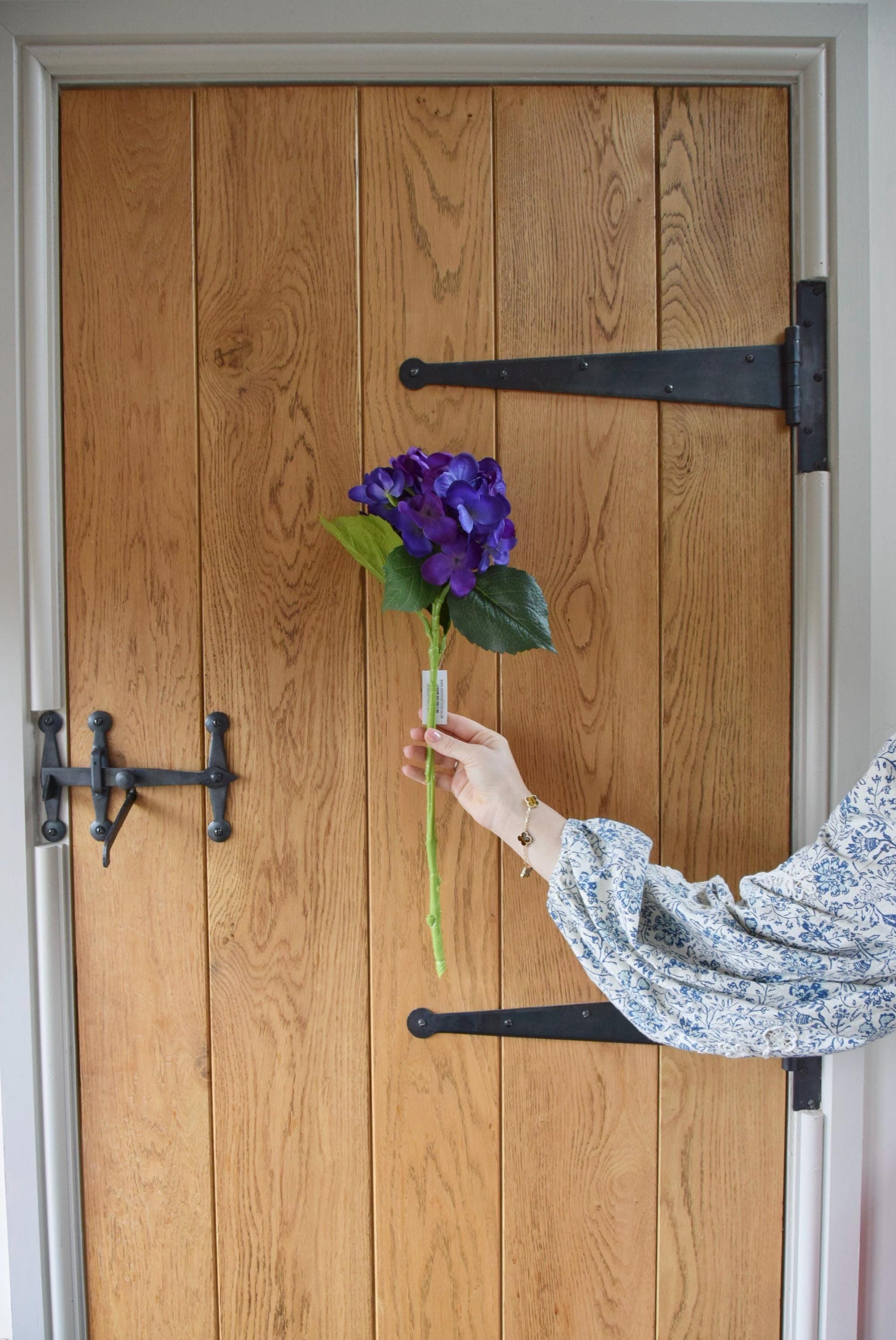 Artificial purple hydrangea displayed against a country style wooden door.