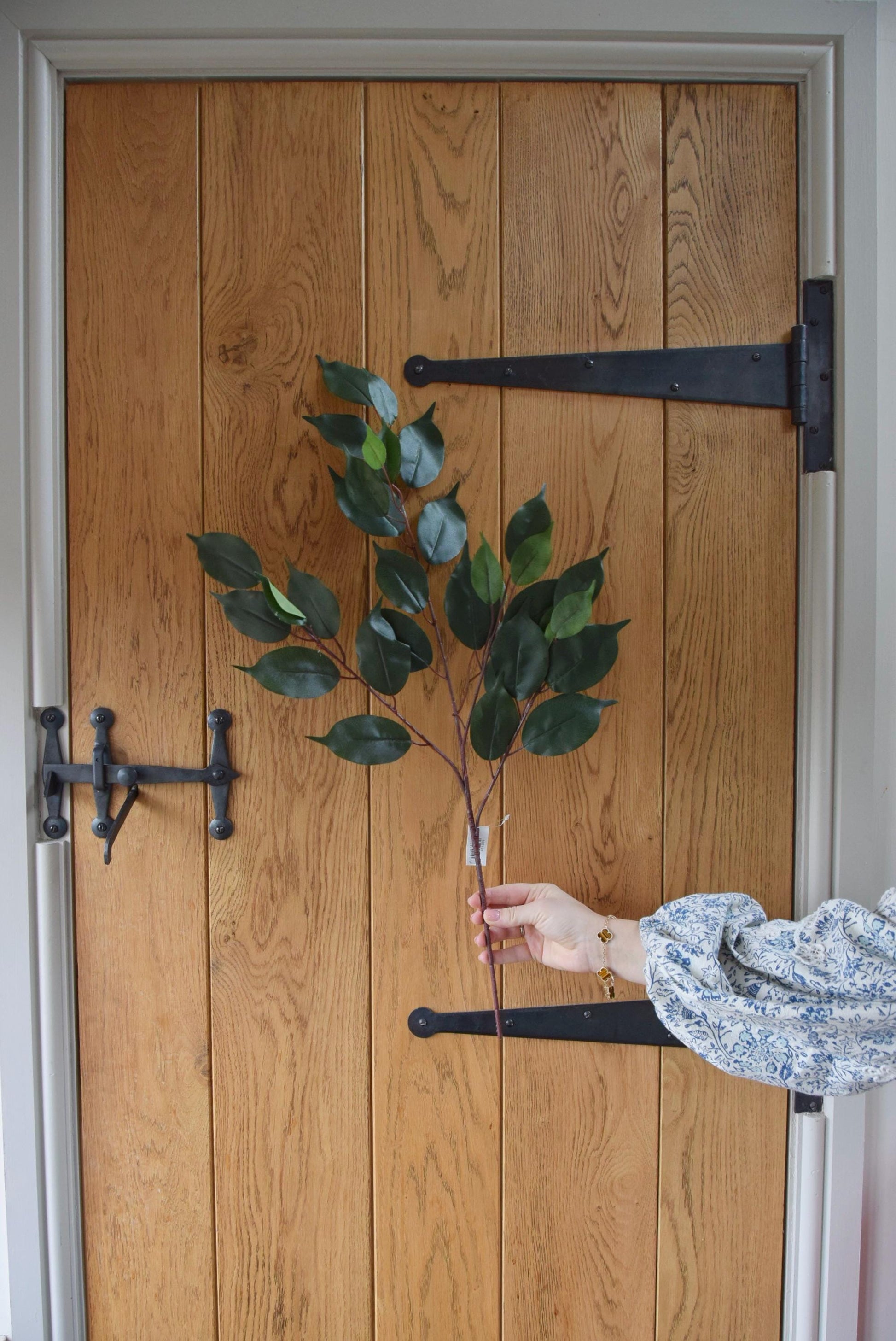 Artificial bay leaf foliage spray displayed against a country style wooden door.