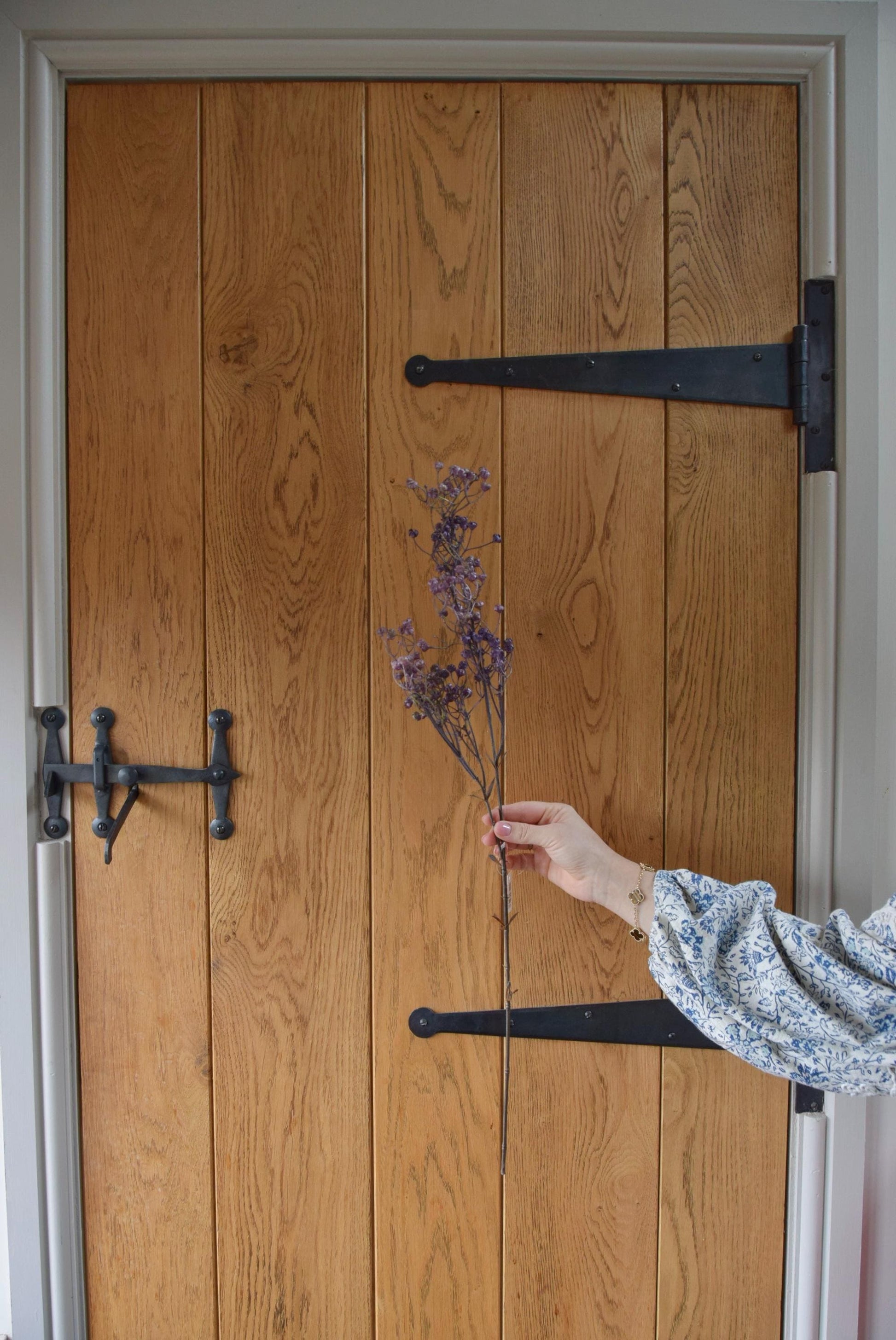 Dried look linum spray displayed against a country style wooden door.
