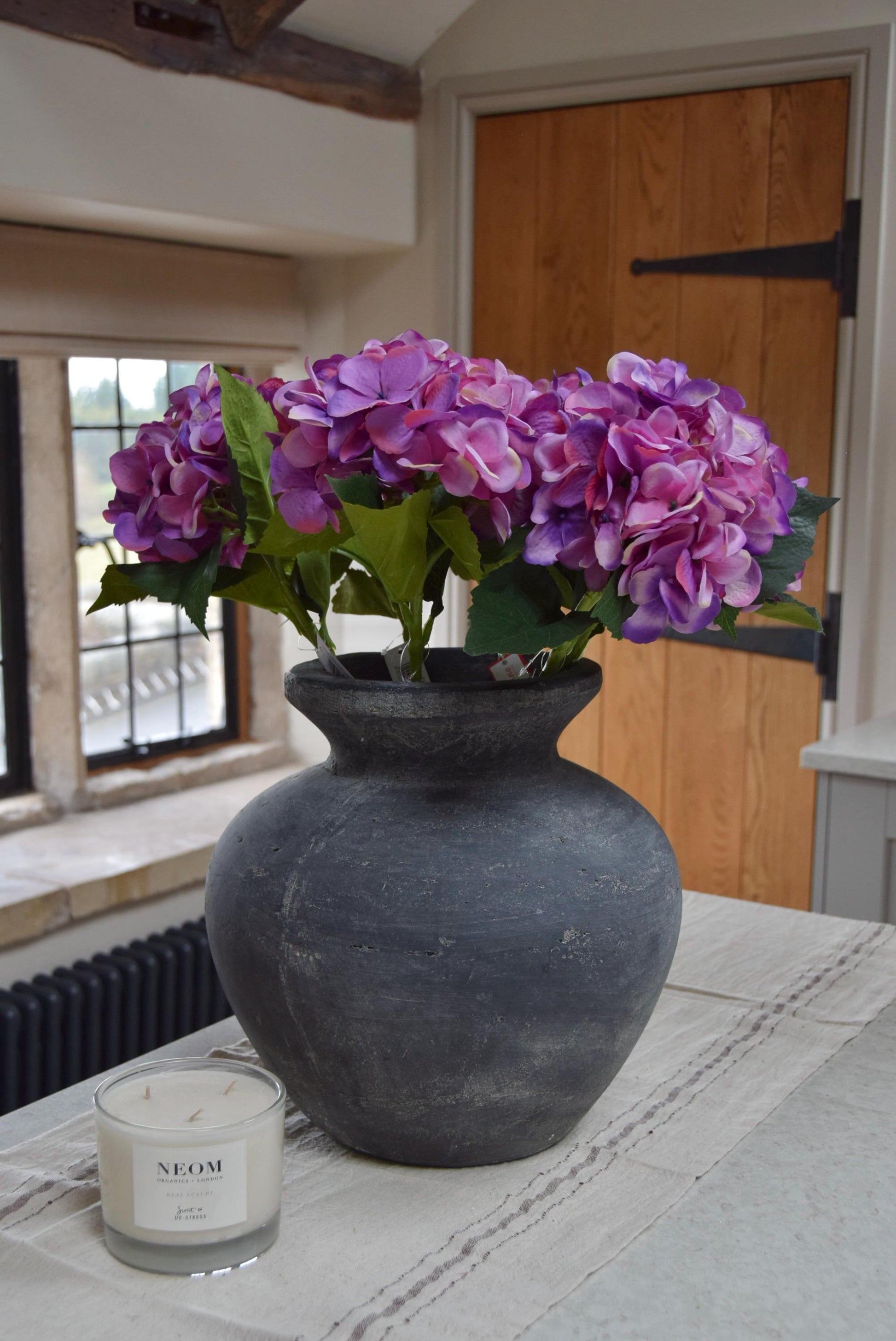 Grey vase placed on a kitchen counter top with purple hydrangeas arranged for home decor
