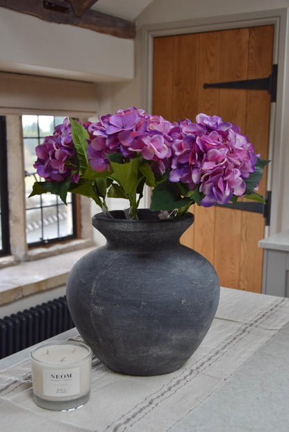 Grey vase placed on a kitchen counter top with purple hydrangeas arranged for home decor