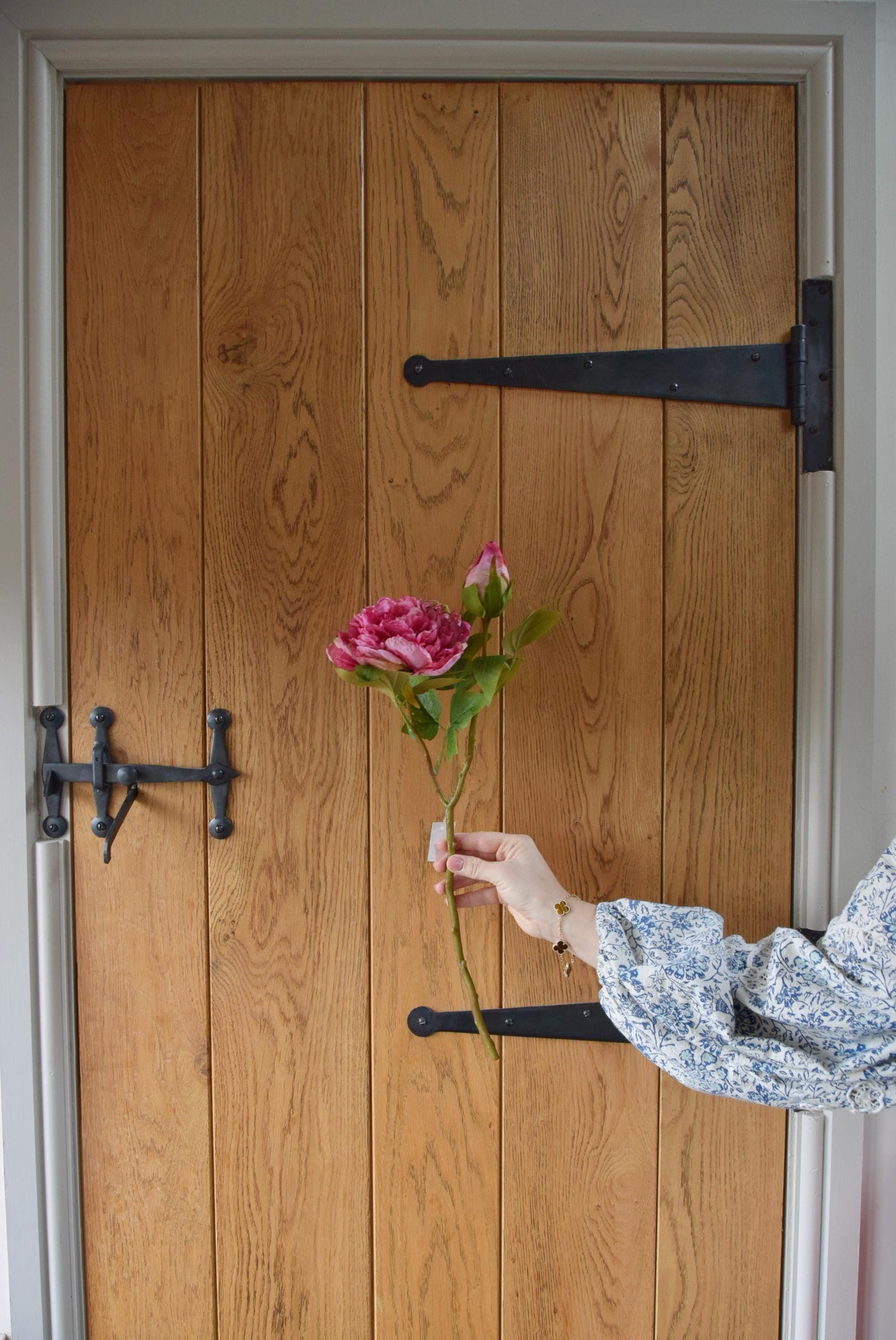 Hot pink peony displayed against a country style wooden door.