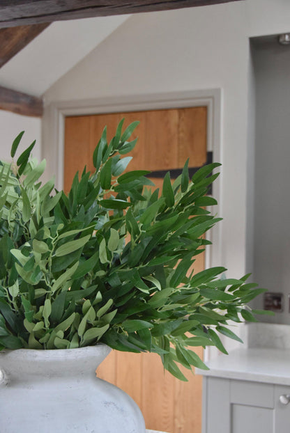 Stone vase on kitchen countertop featuring green foliage leaf stems in a country style kitchen for home decor.