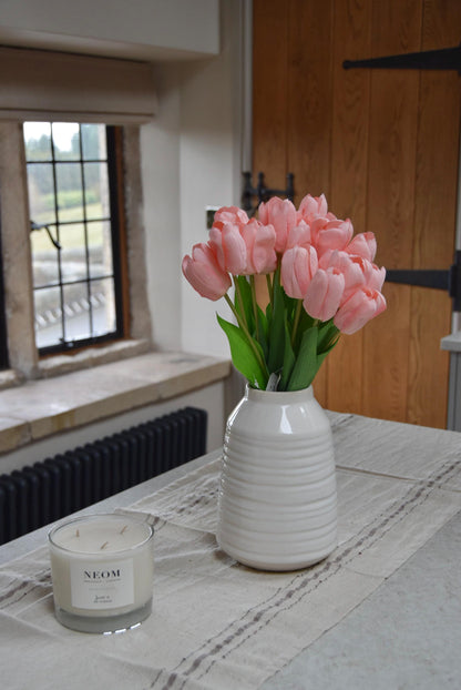 Pink tulips set in a cream vase on a kitchen counter top in a country style kitchen for home decor