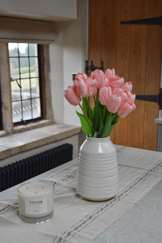Pink tulips set in a cream vase on a kitchen counter top in a country style kitchen for home decor