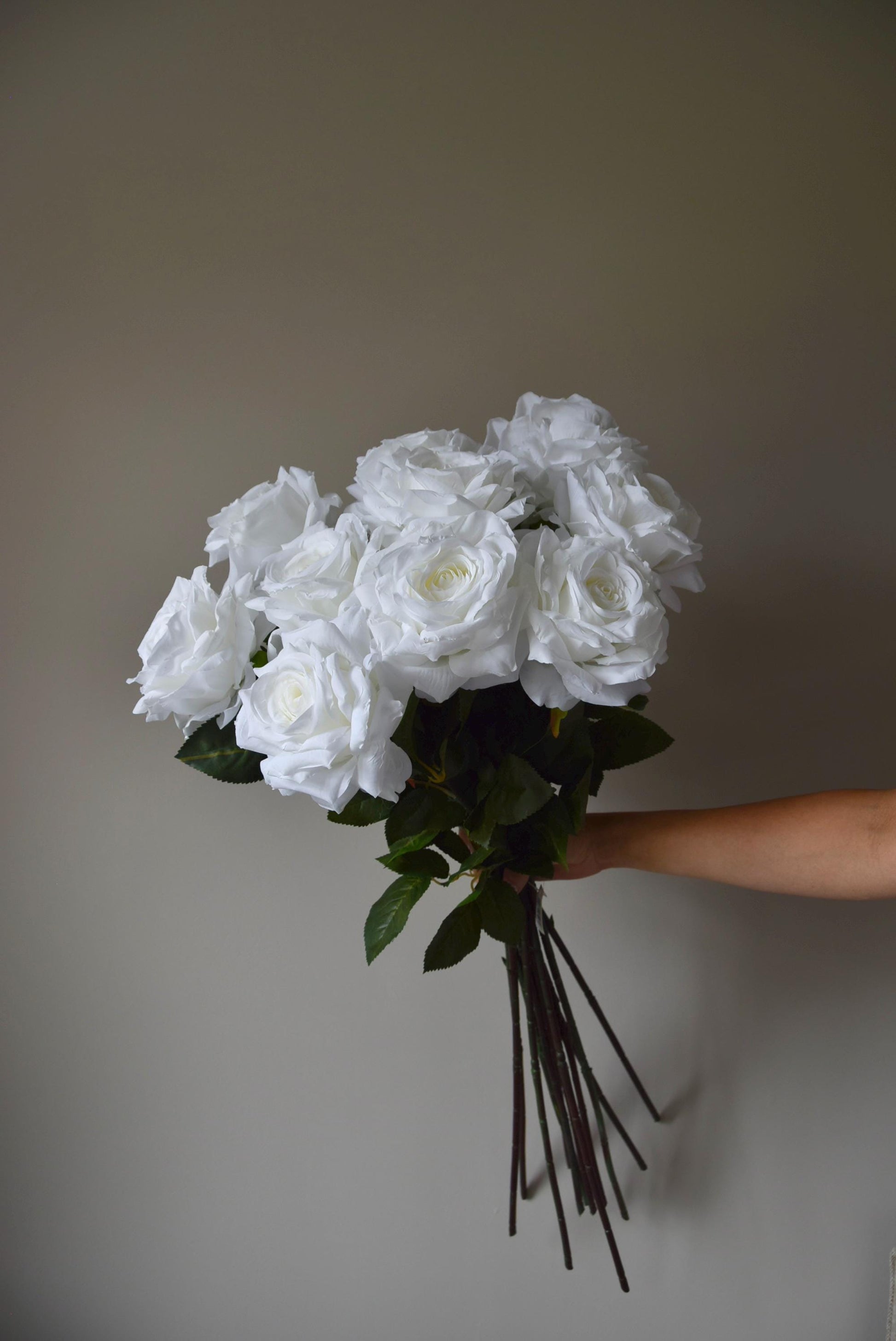 Tall white roses displayed in a bouquet against a neutral background.