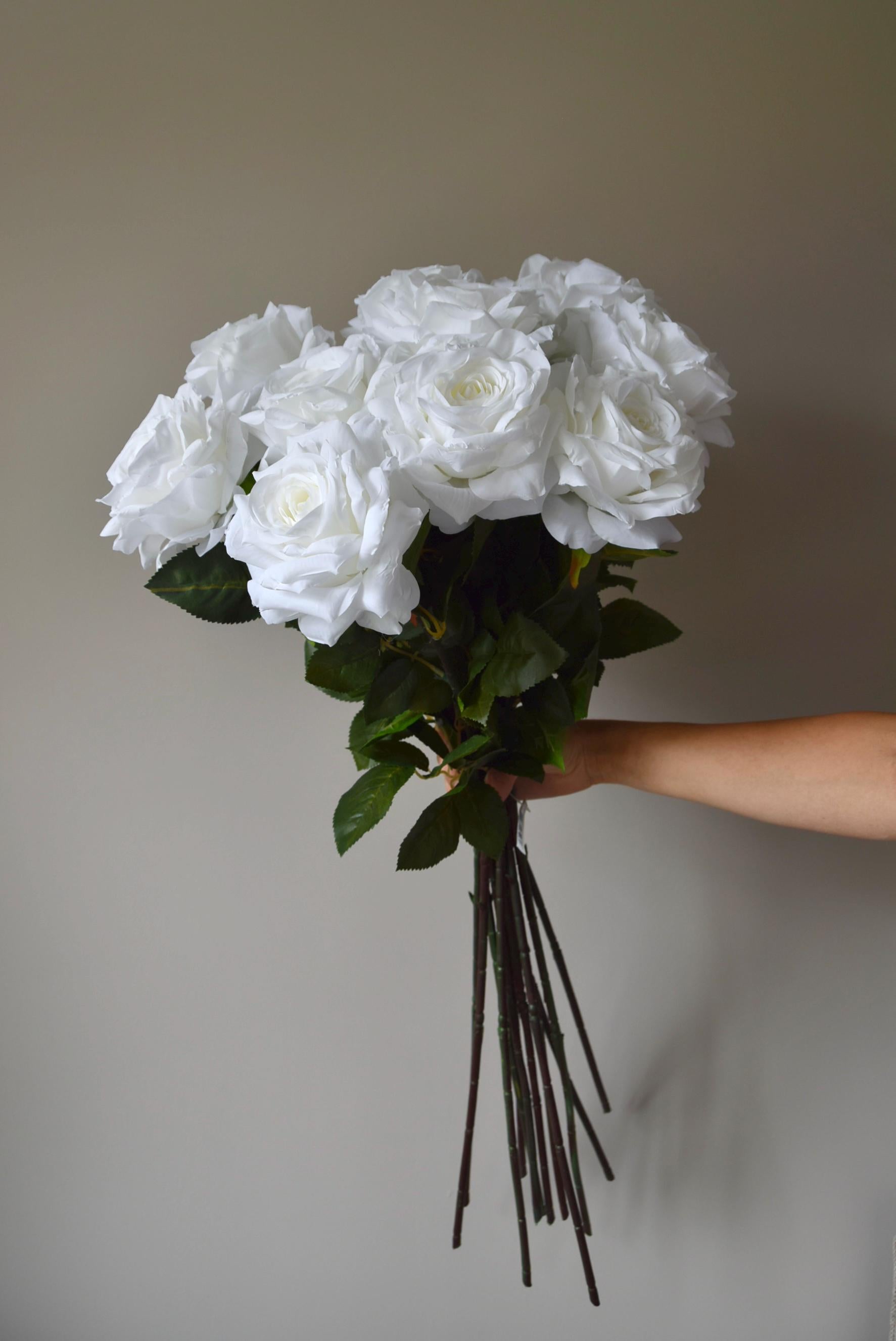 Tall white roses displayed in a bouquet against a neutral background.