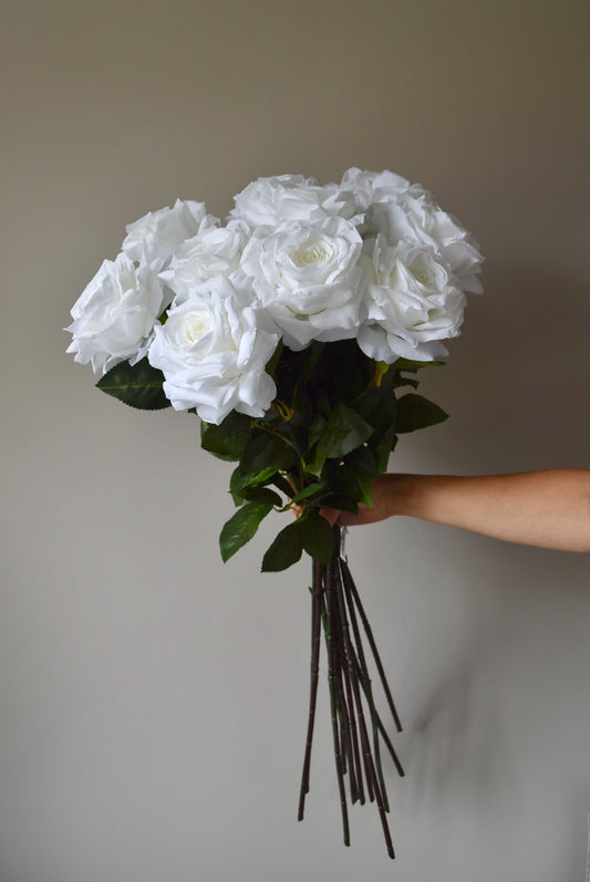 Tall white roses displayed in a bouquet against a neutral background.